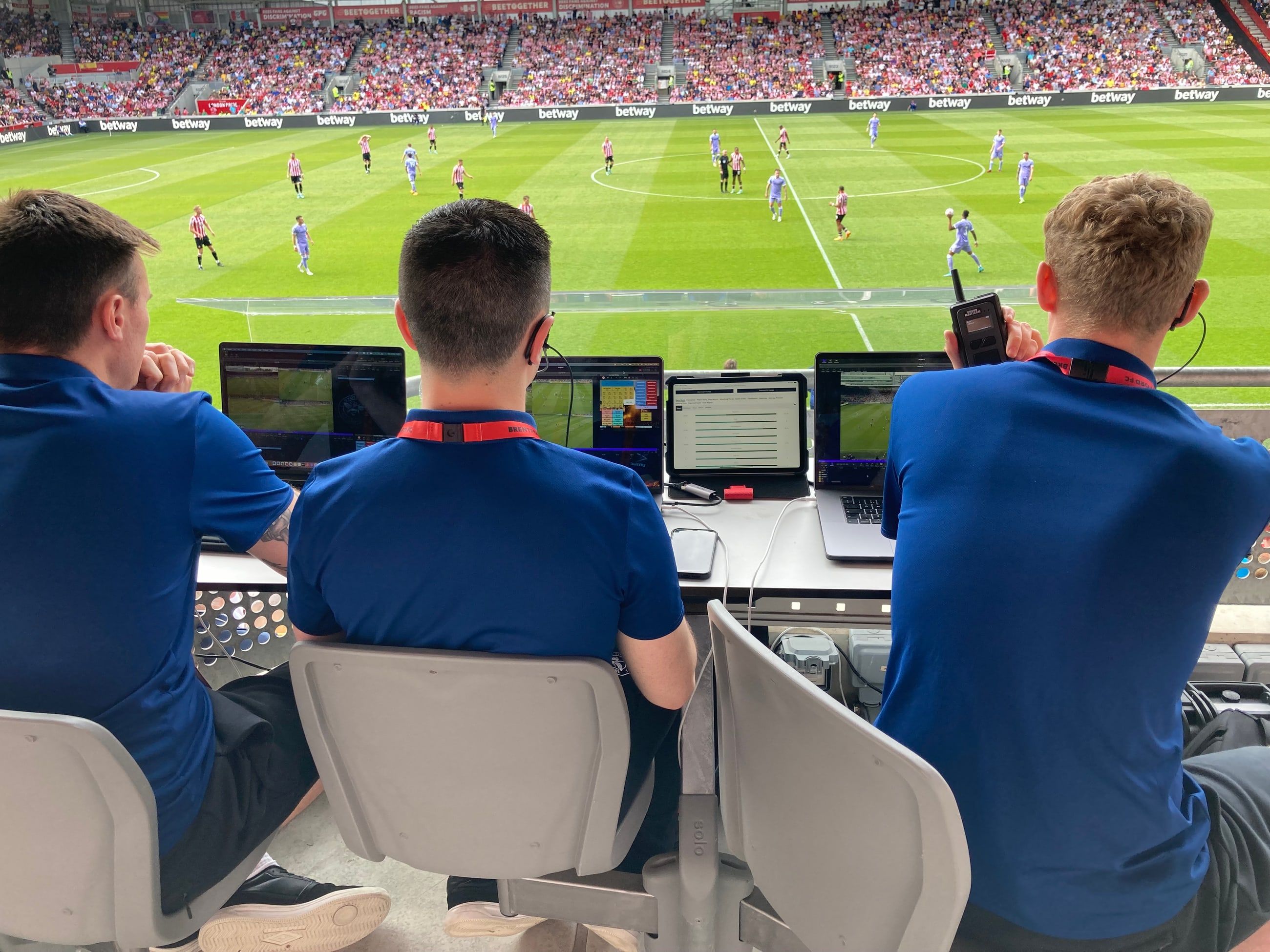 Analysts watching a match from the stand with laptops open.